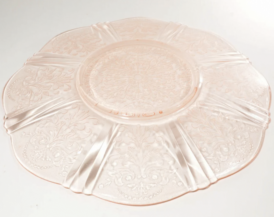 Pink glass charger plate with floral design on a white background depression glass