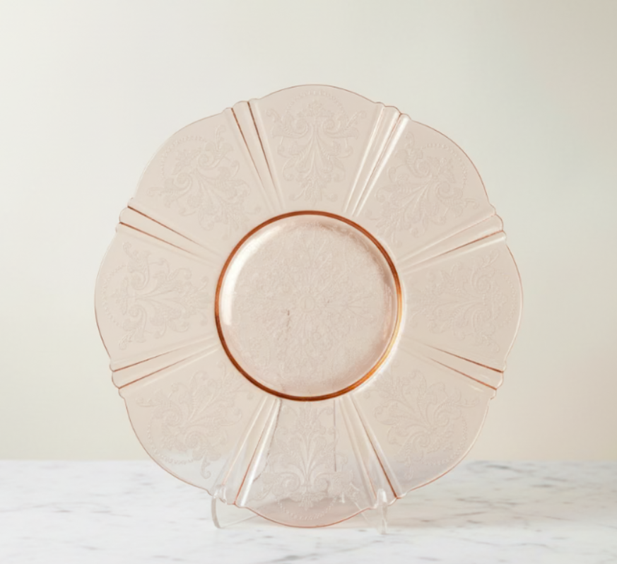 Pink glass plate with decorative rim on a light background