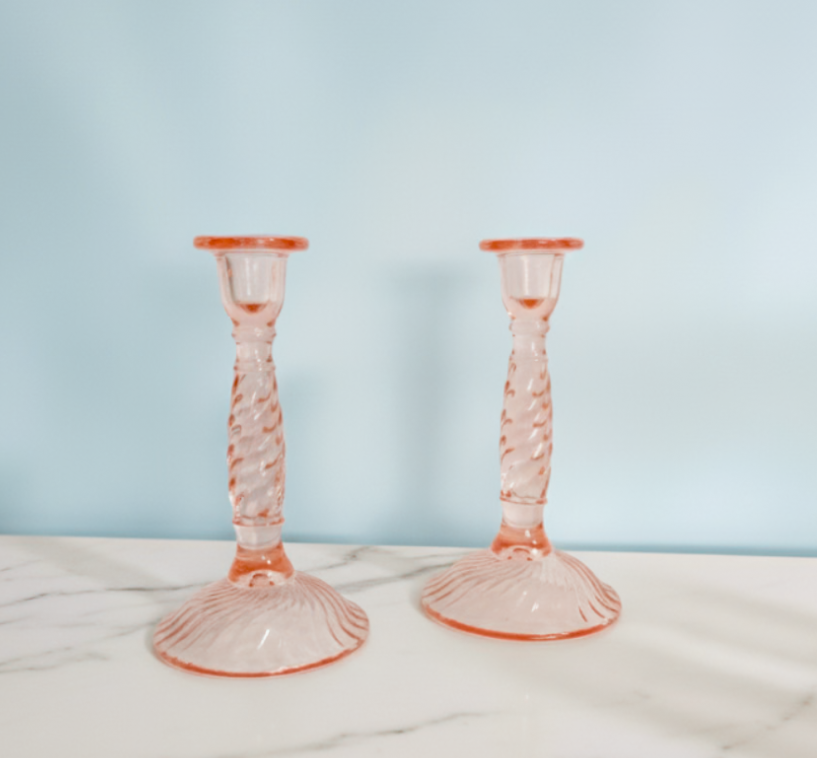 Two pink glass candlesticks on a light blue background