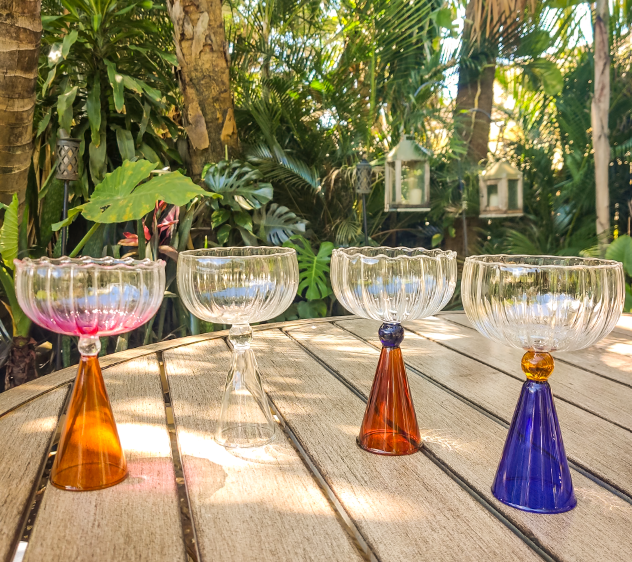 Colorful cocktail glasses on a wooden table with a tropical background