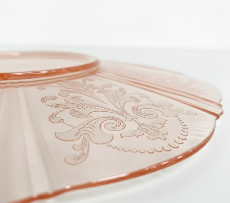 Decorative pink ceramic plate with embossed patterns on a white background